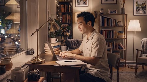 Người đàn ông làm việc trên máy tính xách tay tại góc làm việc ấm cúng tại nhà vào buổi tối.