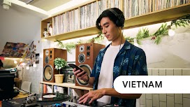 Vietnam. A DJ with his headphones on uses his phone while playing a set.