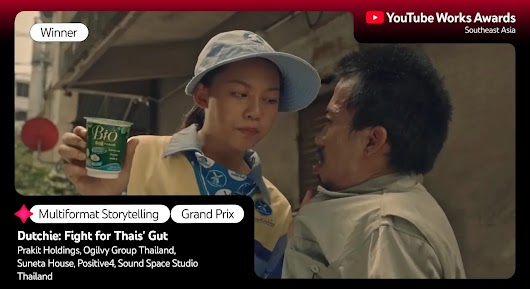 Close-up of a woman in a blue cap and uniform holding a cup of yogurt out to a man looking at her with an intense expression. The setting appears to be an alleyway. The overlay text reads: "Winner," "Multiformat Storytelling," "Grand Prix," and "Dutchie: Fight for Thais' Gut," followed by agency names and "Thailand."