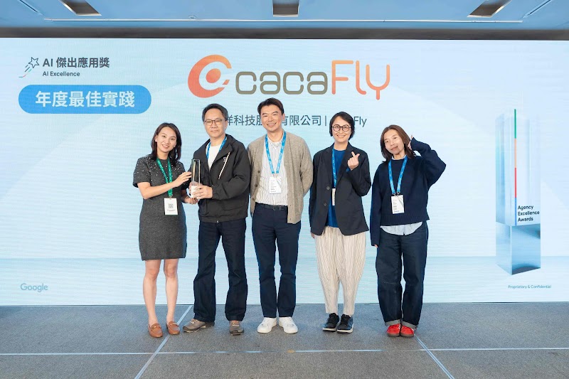 cacaFly團隊五位成員於Google頒獎典禮舞台上祝賀。左起第一位女性著深灰色洋裝、棕色皮鞋；第二位男性著黑色西裝；中央男性著淡黃色長版外套、米色寬褲；第四位女性著深藍色長版外套、眼鏡；第五位女性著深藍色西裝、紅色鞋。所有成員配戴藍色證件帶。背景展示cacaFly品牌標誌與「AI傑出應用獎：年度最佳實踐」藍色獎徽。cacaFly以AI跨媒體策略助力Furbo寵物攝影機品牌，在澳洲市場實現突破性銷售成長，獲2025 Google Award認可。