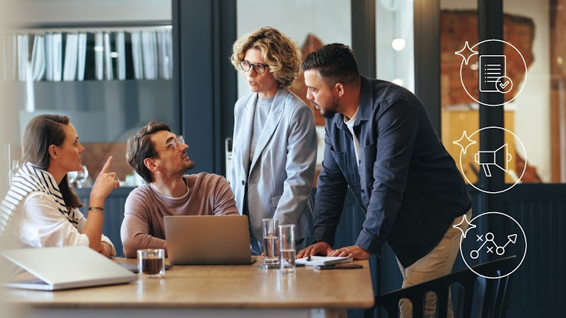Vediamo un gruppo di persone attorno a una scrivania. Due sono sedute con un computer davanti a sé. Due sono in piedi e parlano con le persone sedute. A destra una serie di icone rappresenta le aree chiave del marketing potenziate da Gemini, rappresentato
