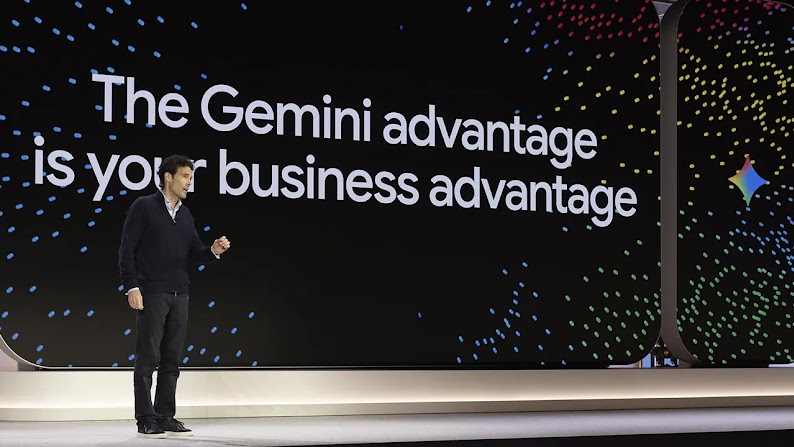 Philipp Schindler speaks from a stage with a large screen behind him. The screen has a black background with rainbow sparkles surrounding the text: The Gemini advantage is your business advantage.