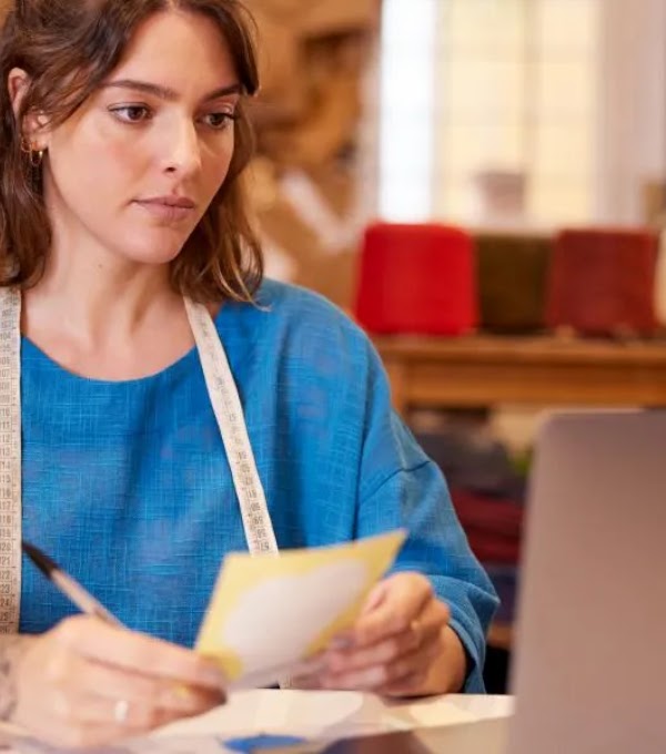 Una mujer, propietaria de una pequeña empresa, está sentada en un escritorio configurando una cuenta de Google Ads en su ordenador portátil.
