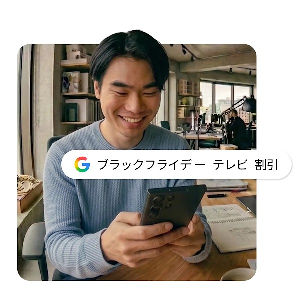 スマートフォンを操作しながら笑顔を見せる男性の画像の上に、「ブラックフライデー テレビ 割引」のGoogle検索バーが配置されたイメージ。