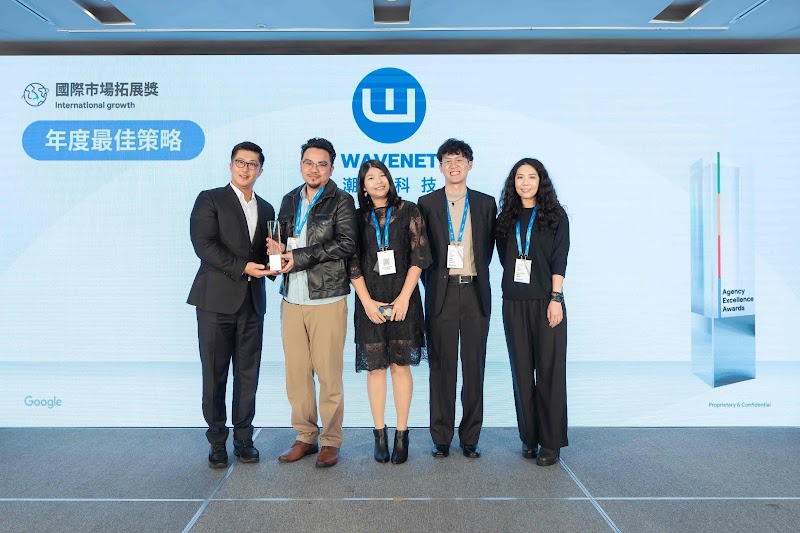 五位業界人士站在藍色背景前領取 Google Agency Excellence Award。背景展示「國際市場拓展獎：年度最佳策略」，左上角有獎項標誌，右側為 Google 獎項標牌。潮網科技以「靈活擴張」策略，透過多渠道整合架構，在全球市場推動晶睿通訊品牌發展，贏得此項年度最佳策略殊榮。