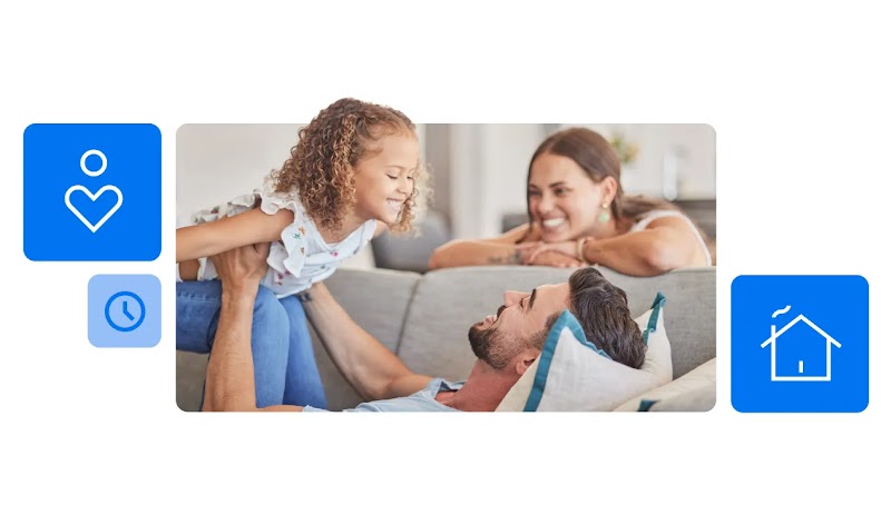 Homem branco e de cabelo preto brinca com uma criança branca de cabelos claros e cacheados. Ao lado, uma mulher branca de cabelos castanhos sorri enquanto os observa.