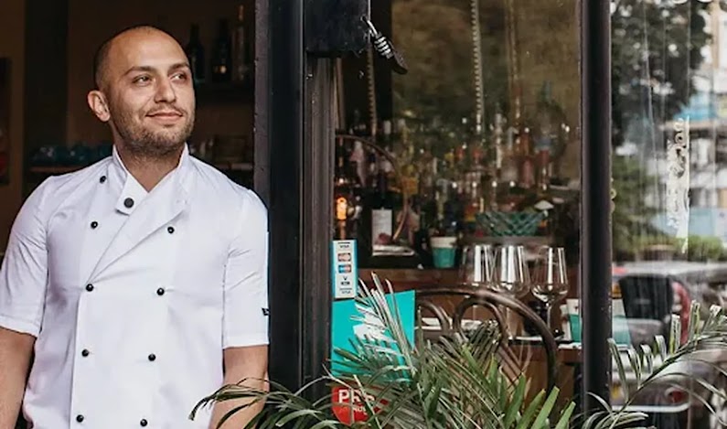 A chef at Belgrave Restaurant looks out of the door into the London neighborhood.