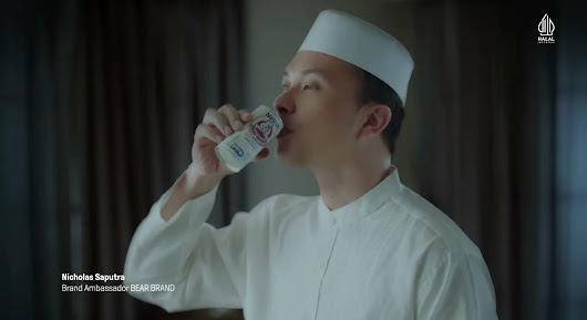 A video thumbnail of a man wearing a white peci cap and baju koko drinking from a can of Bear Brand milk.