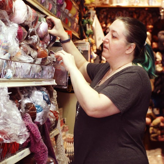 선반에서 털실을 꺼내고 있는 소매업 Cook’s Arts & Crafts의 비즈니스 소유자 이미지