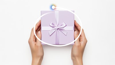 A pair of hands holds a silver-gray gift box, tied with a satin ribbon. The box is circled by a white line and the radiant icon for Circle to Search. 