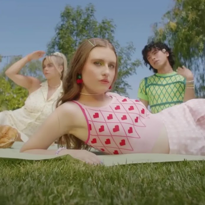 Three people in retro-style summer clothing posing on a picnic blanket in a park.