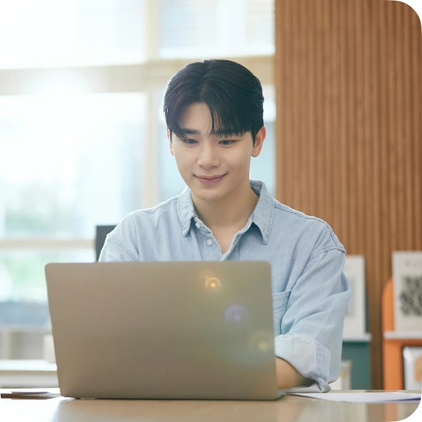 밝은 사무공간에서 노트북으로 작업하며 미소 짓는 남성