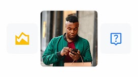 A man with dark skin carries a shopping bag while using a mobile device.