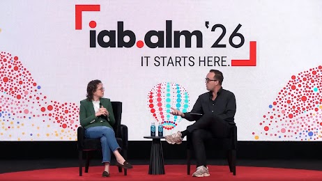 Liz Reid, VP of Search at Google, and Alex Heath, founder of Source, sit in chairs in front of a large pink screen with multicolored dots that reads iab.alm ’26 it starts here.
