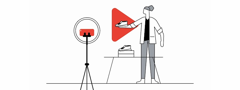 Una mujer con pelo enrulado y saco blanco muestra a la cámara un par de zapatos. Detrás de eso, el logo de YouTube en rojo. A la izquierda, un trípode con un teléfono móvil apuntando al zapato.