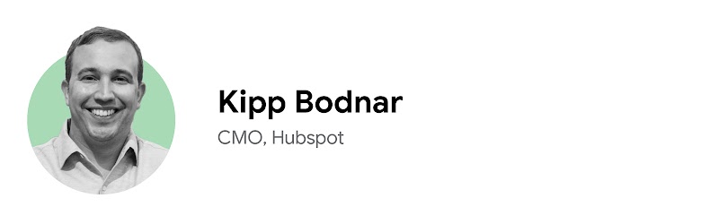 Kipp Bodnar, CMO di Hubspot, sorride in modo amichevole in una foto ritratto in bianco e nero su uno sfondo verde chiaro. Ha gli occhi e i capelli corti scuri, la pelle chiara e indossa una camicia bianca con collo abbottonato.