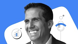 Un ritratto in bianco e nero di Vincenzo Riili su sfondo blu. Alle spalle di lui, una forma bianca. Sulla destra in basso un grafico a colonne che indica crescita, mentre sulla sinistra un microfono con dettagli blu.