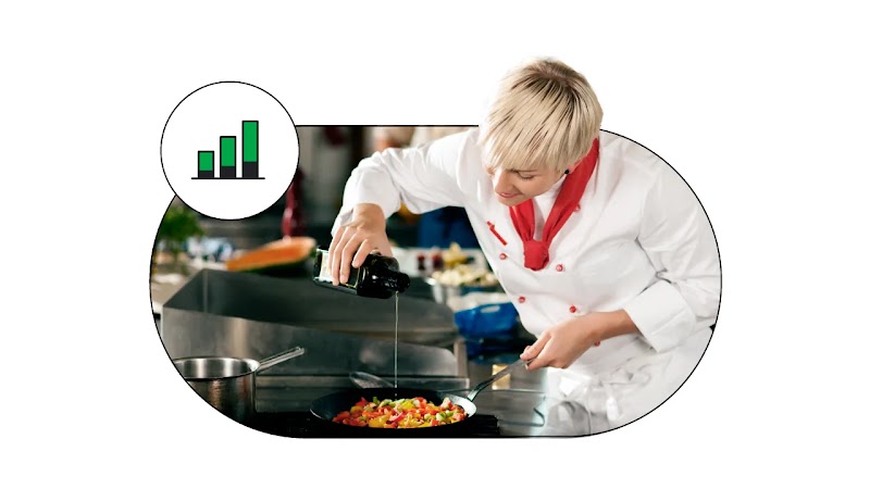 A chef in whites and a red neckerchief is standing over a pan on the stove, drizzling oil over its contents. To the top left of the photo, a green incremental bar graph icon.