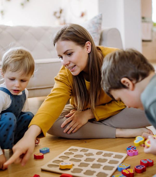 A woman playing with her two kids with montessori themed toys