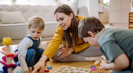 A woman playing with her two kids with montessori themed toys