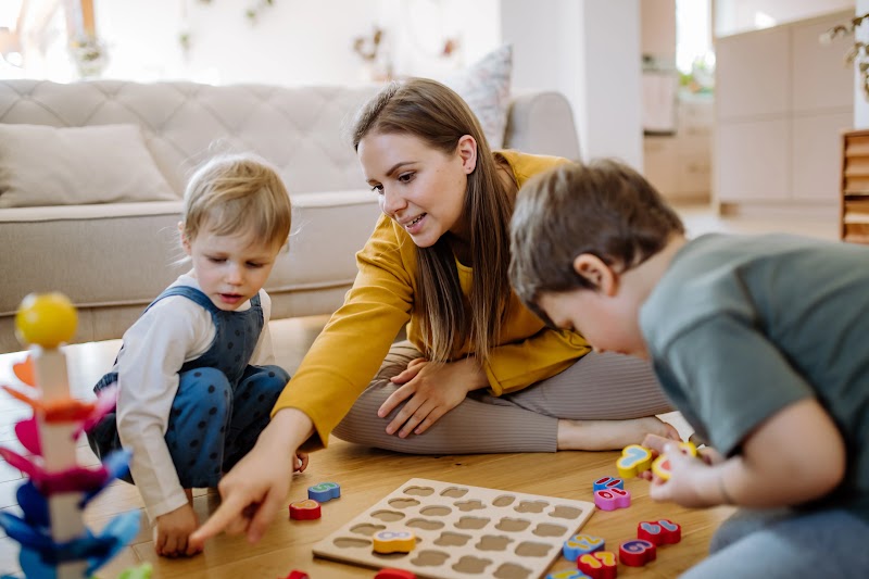 A woman playing with her two kids with montessori themed toys