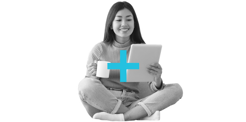 A Hong Kong woman sitting cross-legged on the floor while holding a tablet and a coffee mug