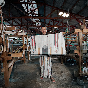 A man showing his woven cloth to the camera