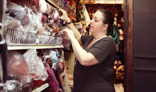 Image of retail Business Owner of Cook’s Arts & Crafts pulling some yarn from a shel