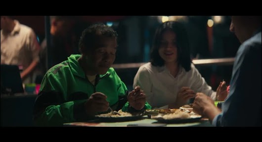 A video thumbnail showing an older man in a green jacket and a smiling young woman sharing a meal together at night.