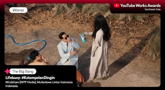 A man in a lab coat and sunglasses is crouching outdoors, looking up in shock at a woman in a long white dress (resembling a ghost figure) who is handing him a bottle of cleaner. Another man is lying on the ground next to a blue hose. The overlay text reads: "Winner," "The Big Bang," and "Lifebuoy: #KetempelanDingin," followed by agency names and "Indonesia." 