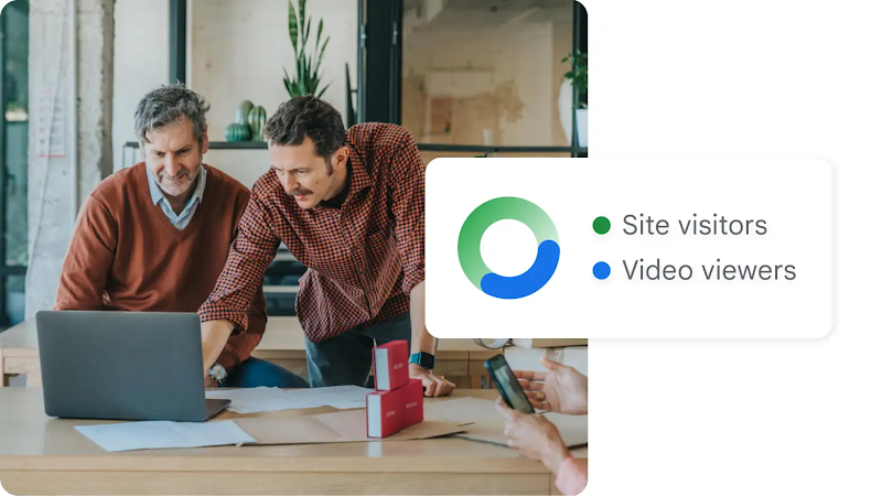 Two men use a laptop, surrounded by a pie chart