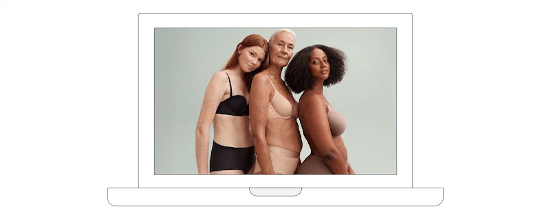 On a laptop screen, three female models with different body types pose in their undergarments. From left to right: a young, red-headed woman with pale skin; an elder woman with white hair; and a young dark-skinned woman with short, curly hair.