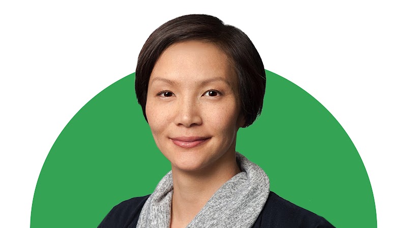 Elissa Lee, directora sénior de Medición y Optimización de Medios de Google, sonríe sobre un fondo verde. Lee tiene la piel clara, los ojos oscuros y el pelo corto y oscuro. Lleva una chaqueta azul oscuro y un jersey gris de cuello holgado.