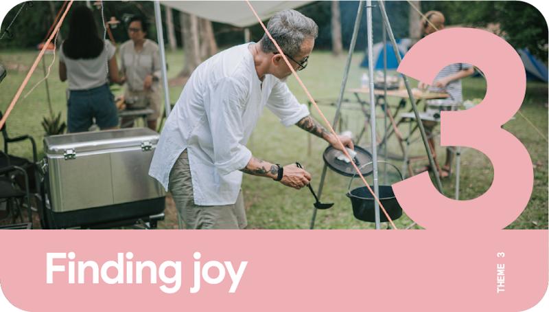 Theme 3: Finding joy. A man with gray hair cooking outdoors during an overseas camping trip.