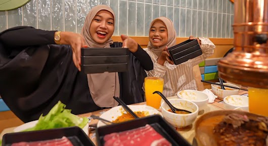 
The video thumbnail depicts a high-energy shot of the content creator and a guest taking part in the "Eating Contest: Who Eats The Most!" challenge, likely surrounded by large servings of food to represent the competitive nature of the challenge. 