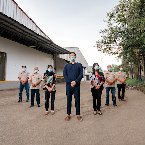 A team standing together outside of their manufacturing facility