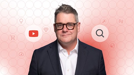 Against a red background, a photo of Mark Ritson. He is wearing glasses and is smiling slightly. To the left, a YouTube icon. To the right, a magnifying glass icon. More icons, like a shopping trolley and a price tag, are in circles on the red background.