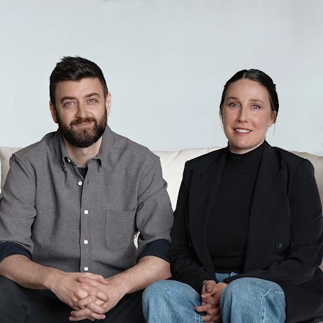 Derek Reynolds and a colleague from Root Science sitting together on a white couch, smiling at the camera.