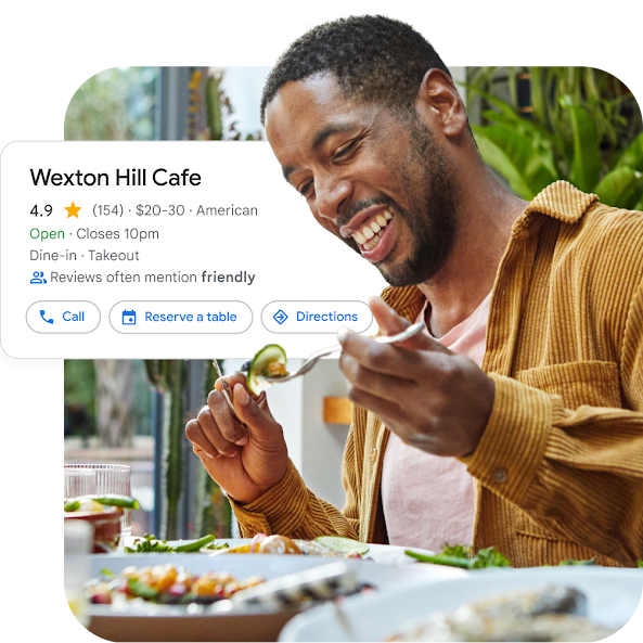 A man seated in a cafe smiling and eating with the UI of the restaurant’s Local Services Ad overlayed.  