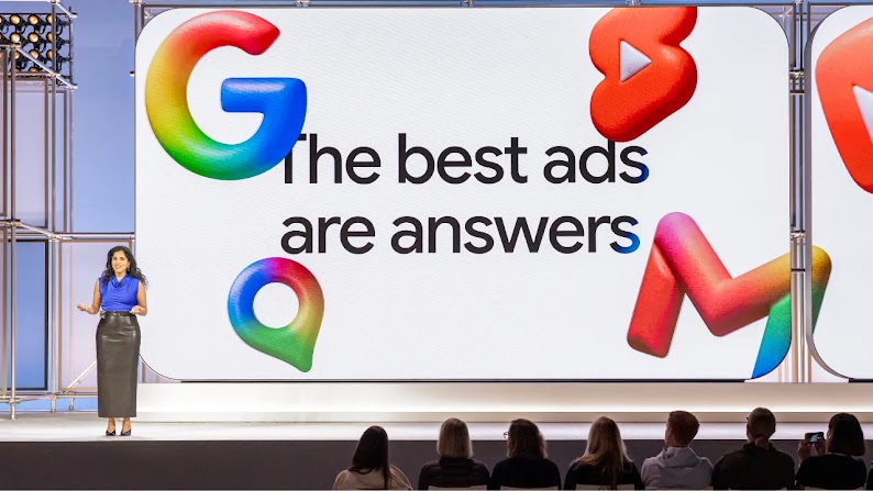 Google executive Vidhya Srinivsan speaks to an audience from the Google Marketing Live stage. A large screen behind her displays a slide from her presentation, reading “The best ads are answers.” Google logos hover around the words like balloons.