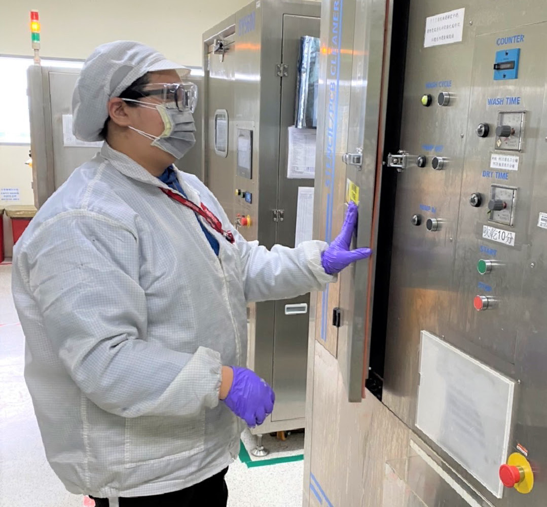 A supplier wearing purple gloves, a white shirt, face mask, head covering and eye glasses while at work
