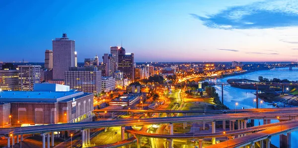 nighttime city view with buildings, roadways and river