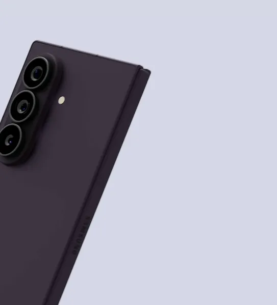 Ponsel Samsung berwarna hitam tampak miring di atas latar belakang berwarna ungu muda. Tiga kamera ditumpuk di bagian kiri belakang perangkat. 