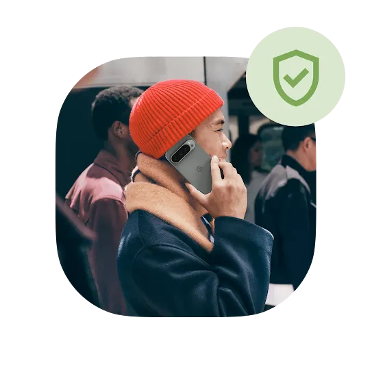 A person wearing an orange beanie is happily talking on their moonstone Pixel 10 phone outside a train station.  A green security shield icon is right above the image. 