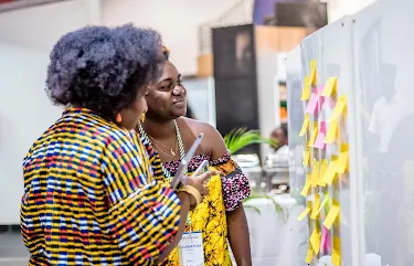 Two women examine a sticky note board at the event.