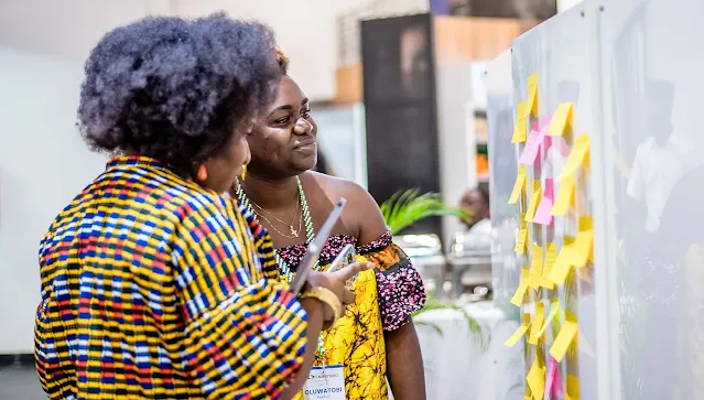 Two women examine a sticky note board at the event.