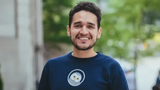 Founder, Jose, smiles in front of a tree lined street.