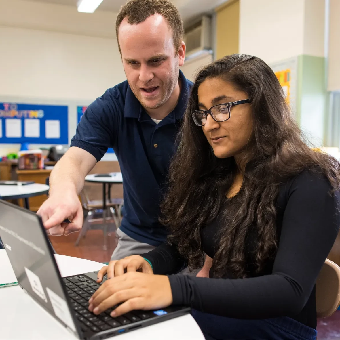 An image of a teacher instructing a student on her laptop.