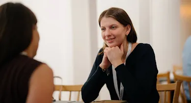 Two women sitting together, smiling and engaged in conversation.