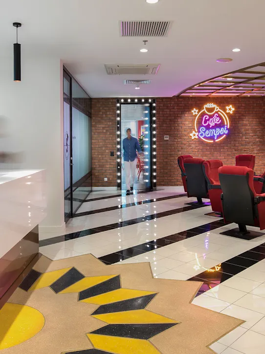 A workspace with brick walls, black-and-white-tiled floors, and red seating.